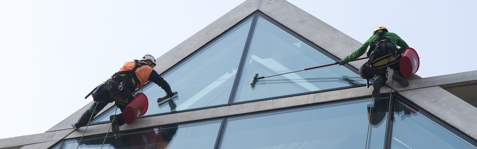 Window cleaning services Chicago. Professional window cleaners on high-rise windows are doing cleaning with mops and other special cleaning tools